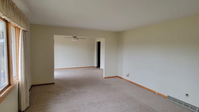 empty room with ceiling fan, plenty of natural light, and light colored carpet