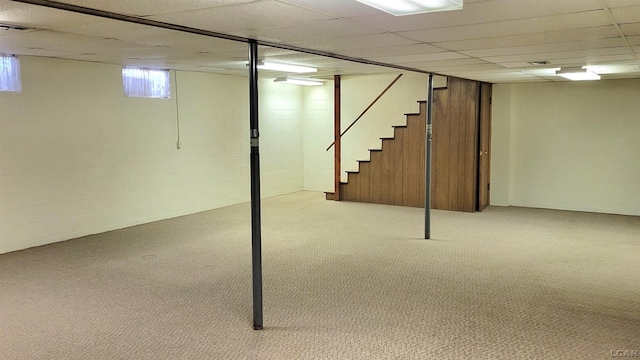 basement featuring a paneled ceiling and light colored carpet