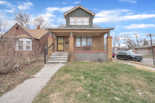 bungalow-style home featuring covered porch and a front lawn