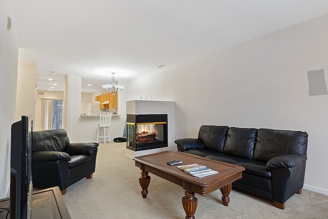 living room with a multi sided fireplace, light colored carpet, and an inviting chandelier