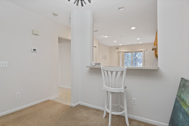 kitchen featuring a breakfast bar, white fridge, kitchen peninsula, and light colored carpet