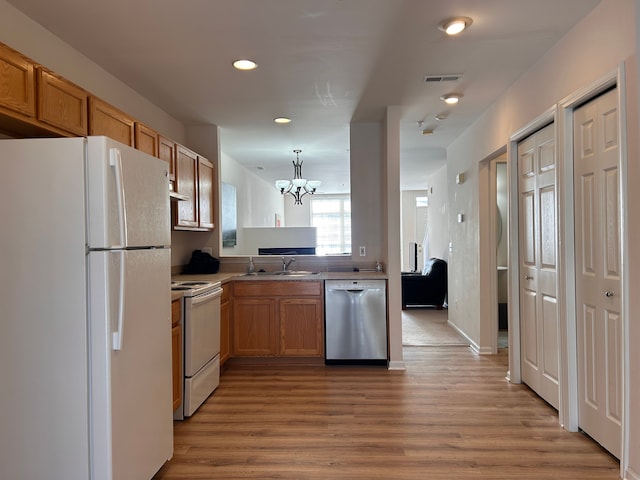 kitchen with white appliances, a chandelier, sink, light hardwood / wood-style floors, and kitchen peninsula