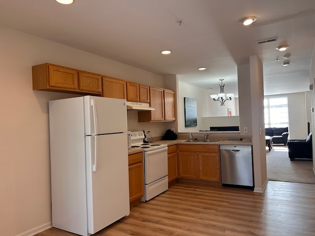 kitchen with white appliances, sink, a notable chandelier, light wood-type flooring, and decorative light fixtures