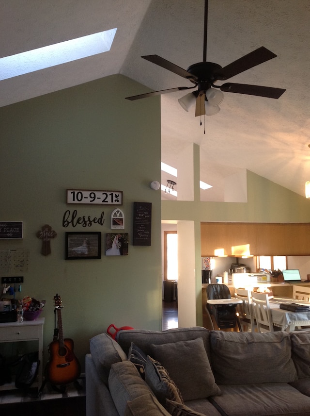 living room with a skylight, ceiling fan, and high vaulted ceiling