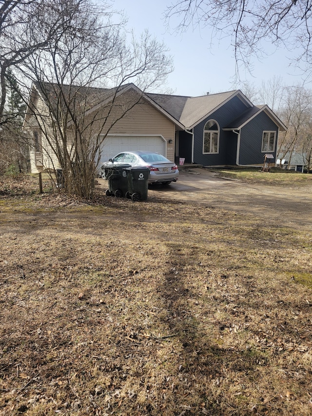 view of front of property with an attached garage and dirt driveway