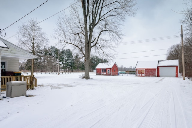 snowy yard featuring a garage and an outdoor structure