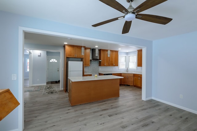 kitchen featuring sink, a center island, white refrigerator, light hardwood / wood-style floors, and wall chimney range hood