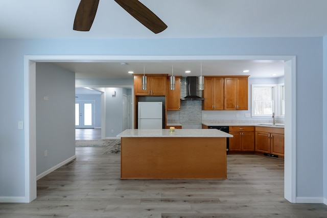 kitchen with wall chimney exhaust hood, sink, hanging light fixtures, a kitchen island, and white fridge