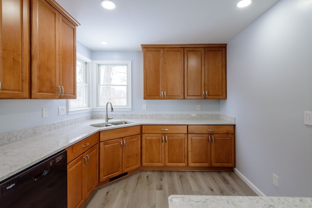 kitchen with light stone counters, light hardwood / wood-style floors, black dishwasher, and sink