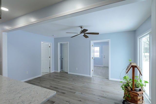 unfurnished living room featuring wood-type flooring, plenty of natural light, and ceiling fan