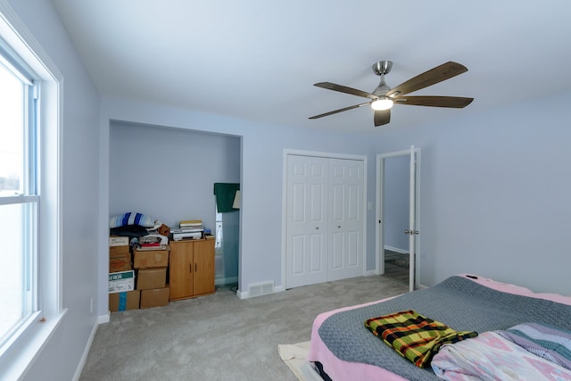 bedroom with ceiling fan, light colored carpet, and a closet