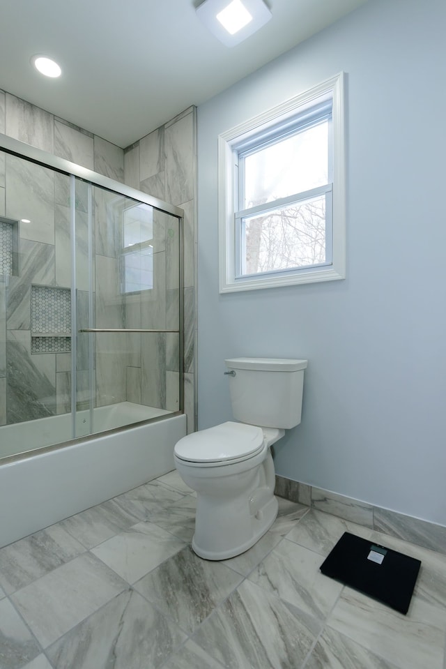 bathroom featuring bath / shower combo with glass door and toilet