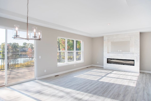 837 Preserve Ln, White Lake, MI 48386 - unfurnished living room with wood finished floors, baseboards, a chandelier, a premium fireplace, and a water view
