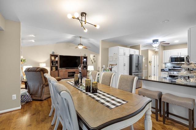 dining space featuring lofted ceiling, hardwood / wood-style floors, and a notable chandelier