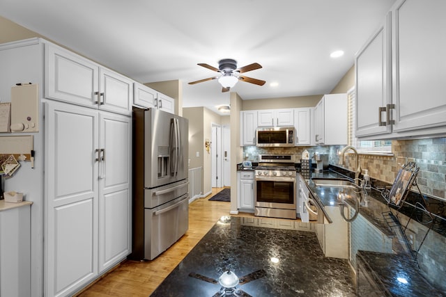 kitchen featuring sink, white cabinets, dark stone counters, and appliances with stainless steel finishes