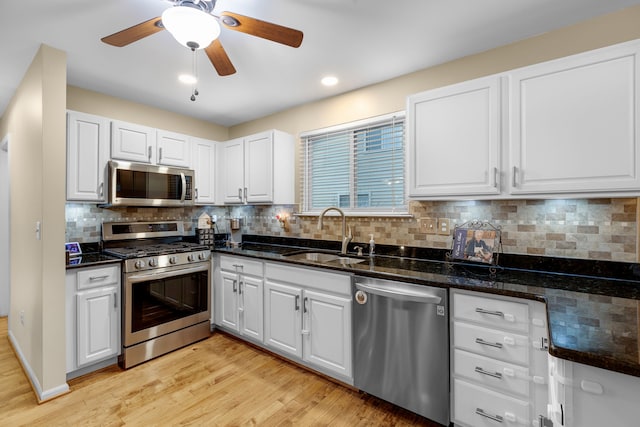 kitchen featuring appliances with stainless steel finishes, white cabinets, backsplash, and sink