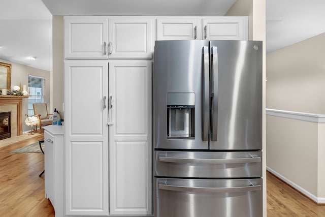 kitchen featuring light hardwood / wood-style flooring, stainless steel fridge with ice dispenser, and white cabinetry