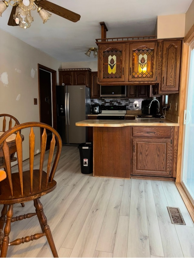 kitchen featuring stainless steel fridge with ice dispenser, light hardwood / wood-style floors, ceiling fan, tasteful backsplash, and sink