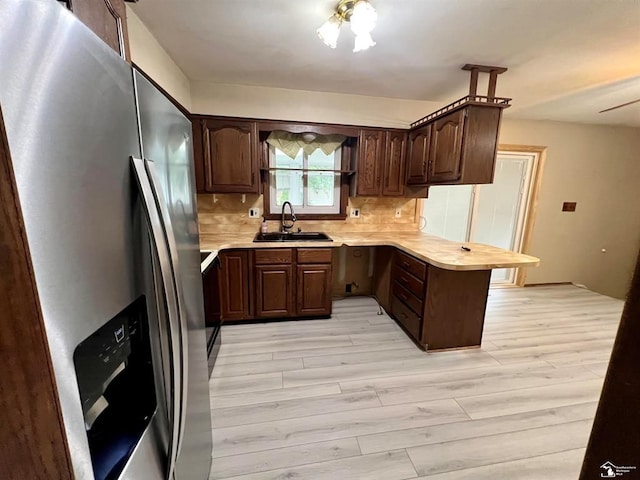 kitchen with dark brown cabinetry, decorative backsplash, sink, stainless steel fridge with ice dispenser, and kitchen peninsula