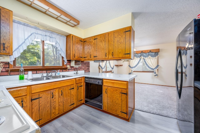 kitchen featuring light wood-type flooring, a textured ceiling, sink, and black appliances