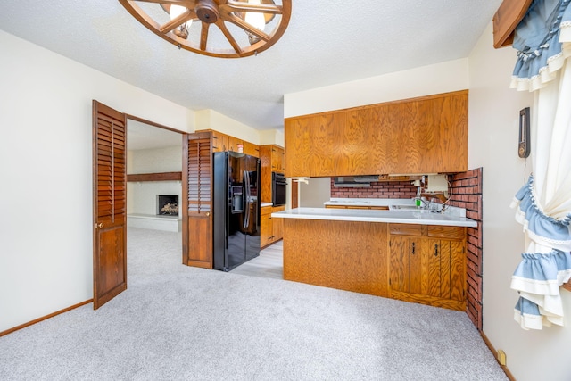 kitchen featuring kitchen peninsula, light colored carpet, black appliances, and a textured ceiling