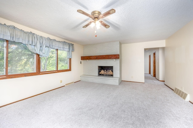 unfurnished living room with a fireplace, a textured ceiling, light colored carpet, and ceiling fan