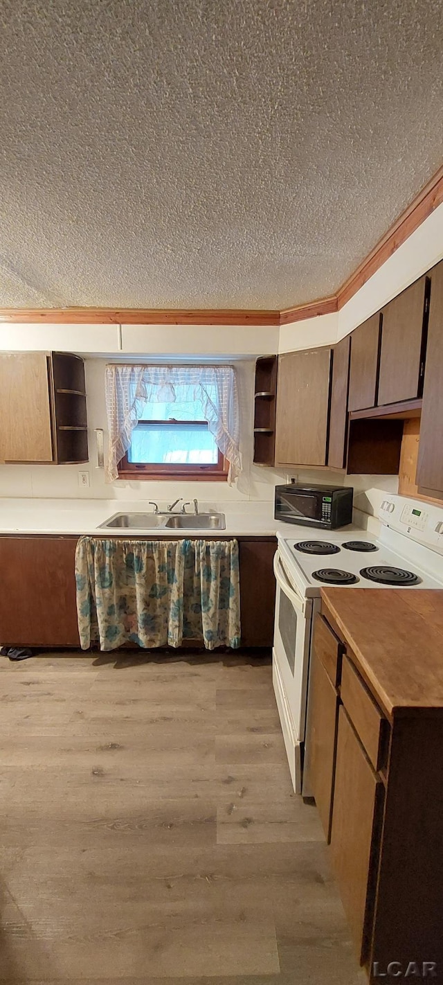 kitchen featuring light wood-type flooring, white electric range oven, a textured ceiling, crown molding, and sink