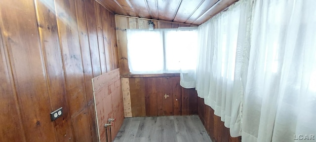 empty room featuring light hardwood / wood-style floors, wooden ceiling, and wood walls