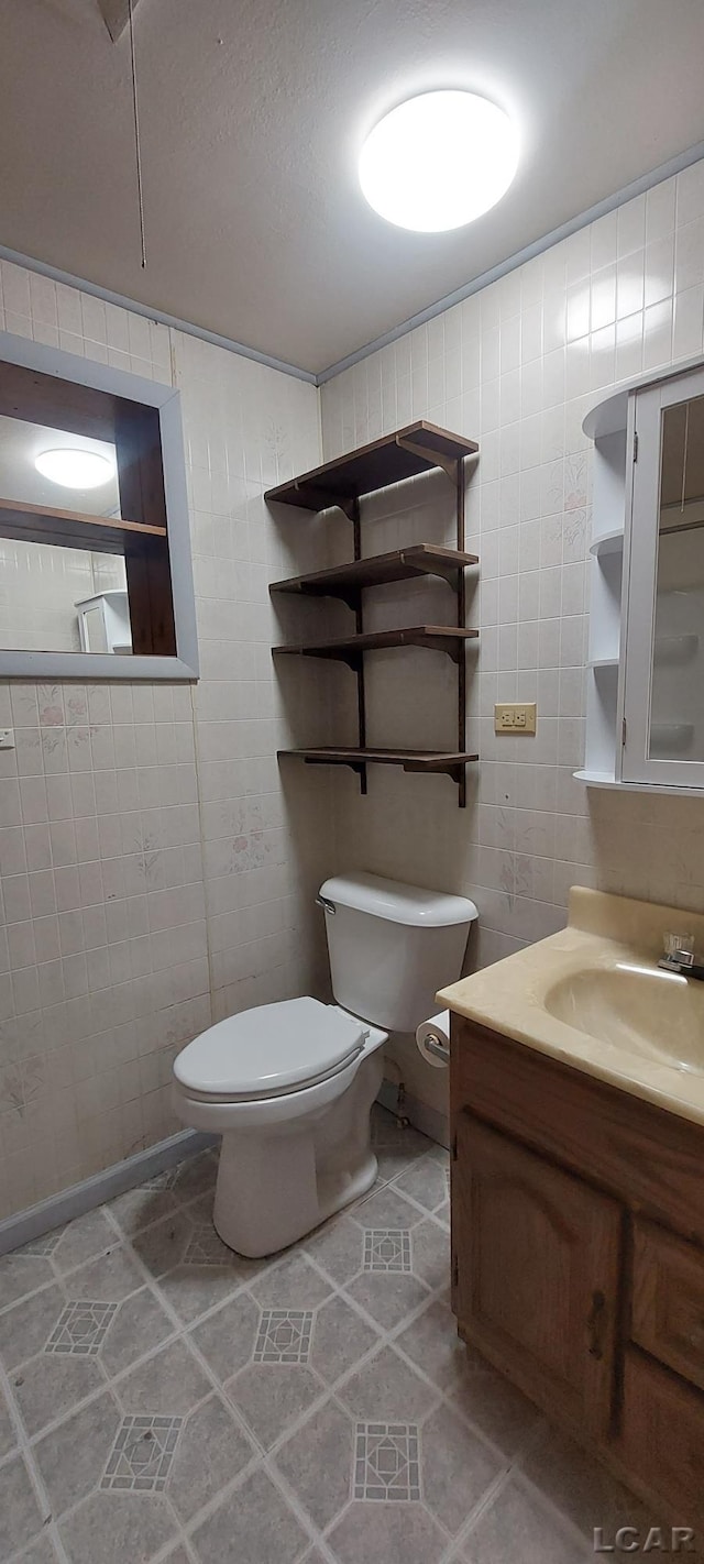 bathroom featuring vanity, toilet, and tile walls