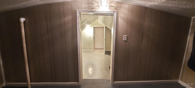 corridor with wood walls and a textured ceiling