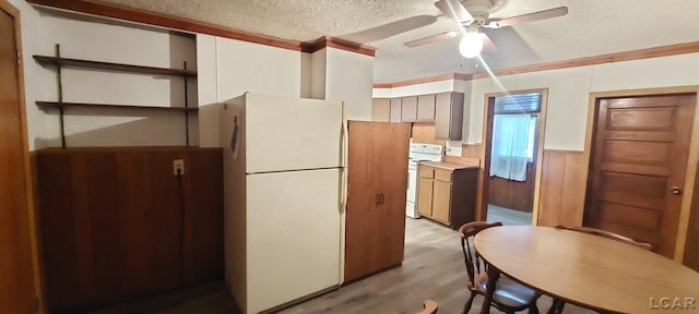 kitchen with ceiling fan, wood walls, light hardwood / wood-style floors, a textured ceiling, and white appliances