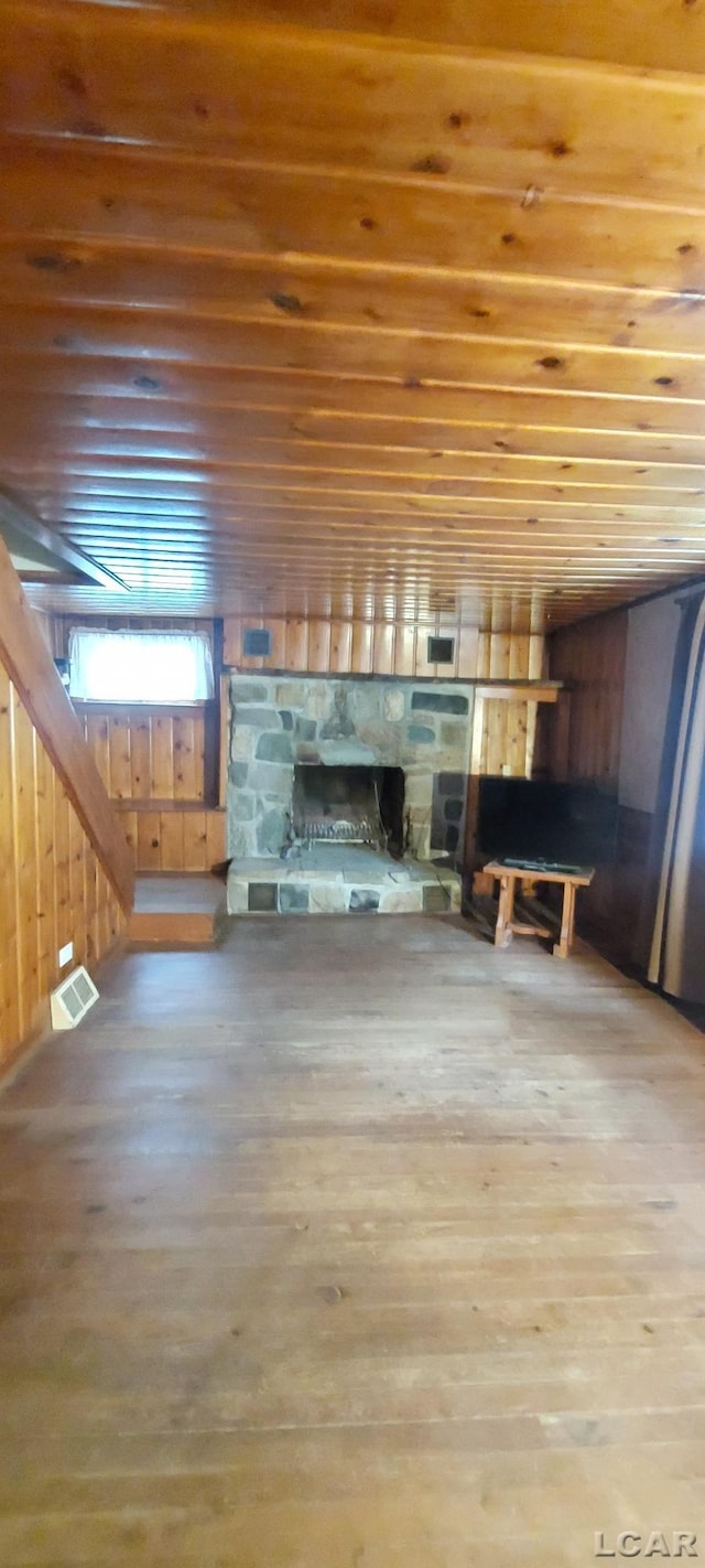 unfurnished living room featuring hardwood / wood-style floors and a stone fireplace