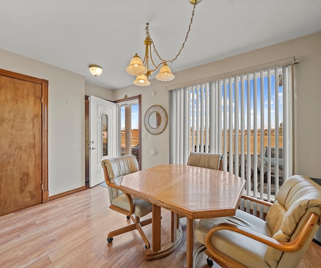 dining space featuring light wood-type flooring, a wealth of natural light, and an inviting chandelier