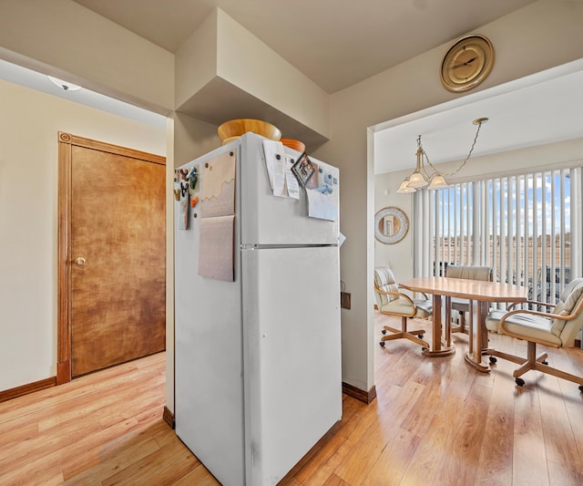 kitchen with white refrigerator, decorative light fixtures, light hardwood / wood-style flooring, and a notable chandelier