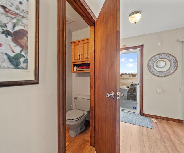 corridor with light hardwood / wood-style flooring and tile walls