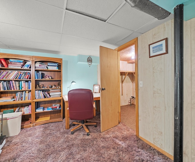 carpeted office featuring a drop ceiling and wood walls