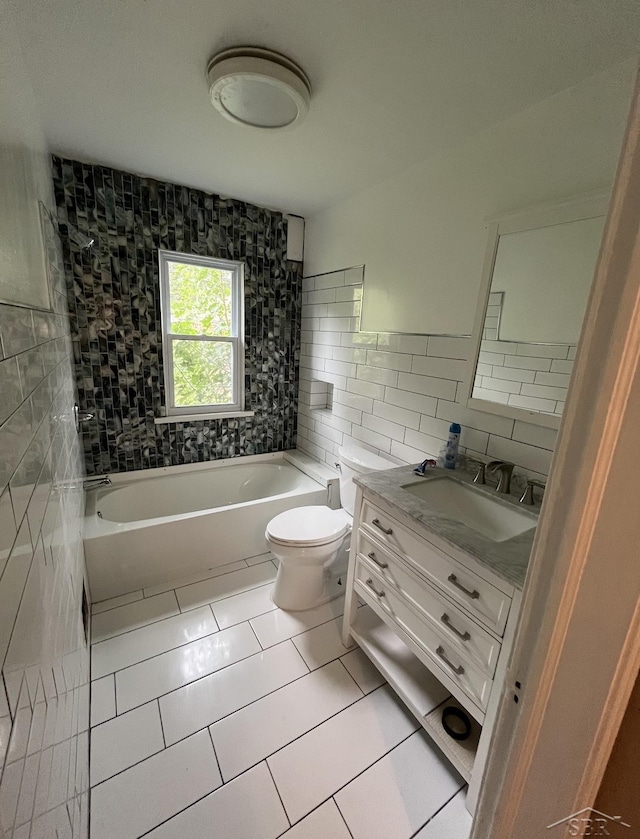 full bathroom with vanity, tile patterned flooring, tiled shower / bath combo, toilet, and tile walls