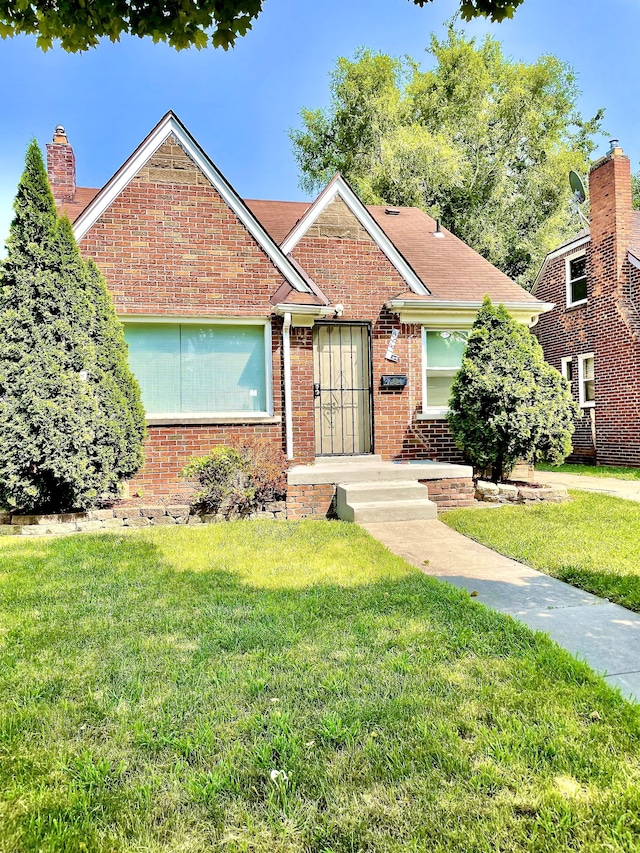 view of front facade with a front lawn, a chimney, and brick siding