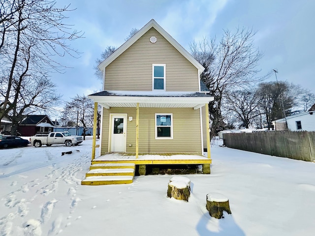 snow covered back of property with covered porch