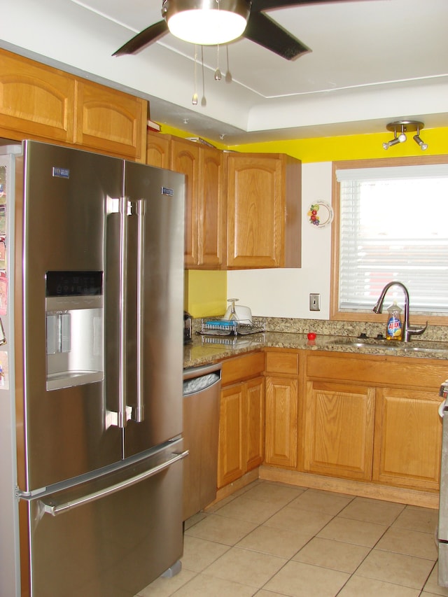 kitchen featuring light stone countertops, stainless steel appliances, a raised ceiling, sink, and light tile patterned floors