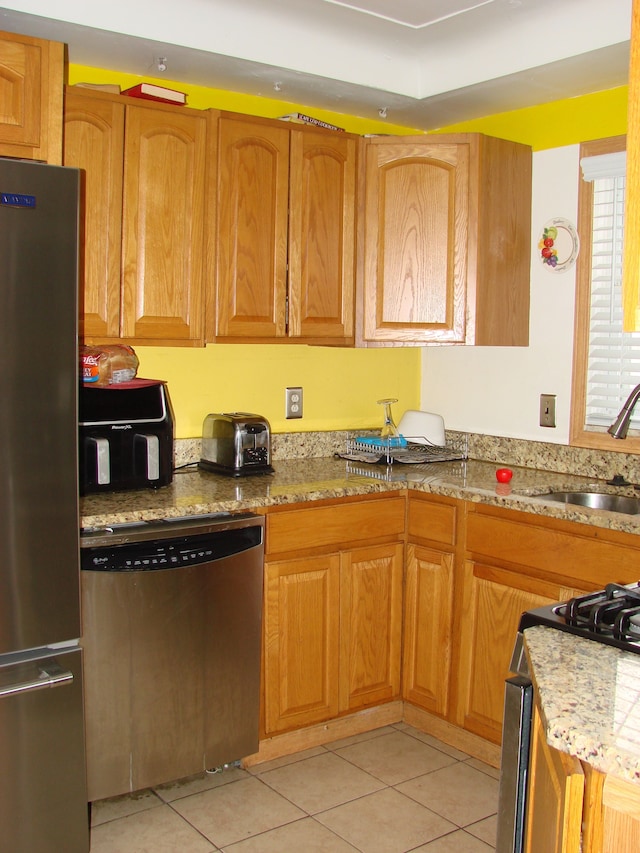 kitchen featuring light stone counters, light tile patterned floors, sink, and appliances with stainless steel finishes