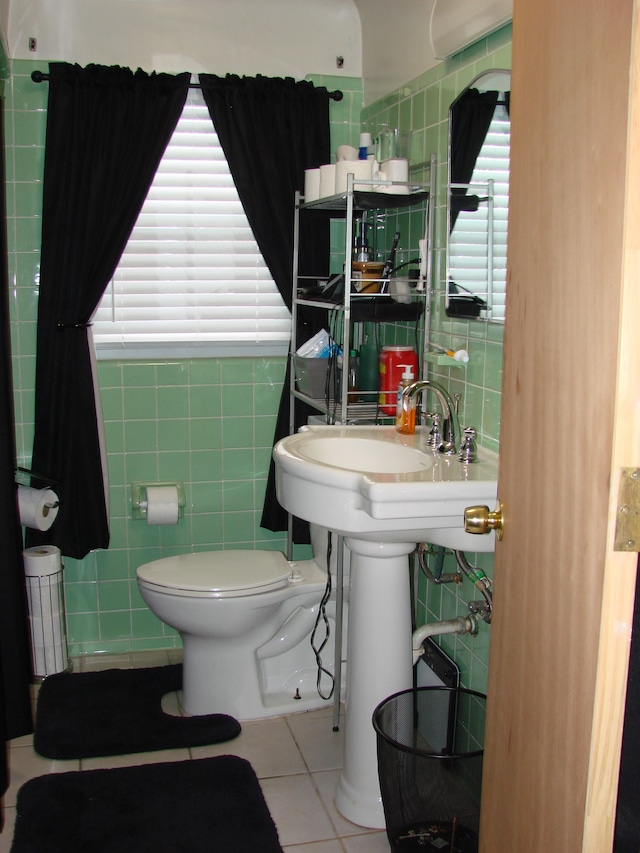 bathroom featuring toilet, tile patterned floors, and tile walls