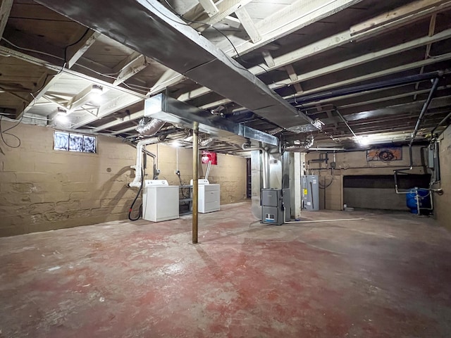 basement with heating unit, electric water heater, and washer and dryer