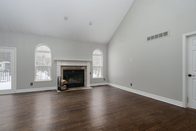 unfurnished living room with high vaulted ceiling and dark wood-type flooring