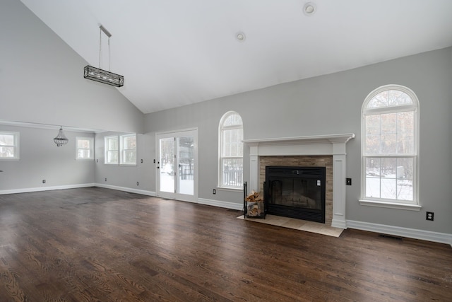 unfurnished living room with dark wood-type flooring, high vaulted ceiling, and a tiled fireplace