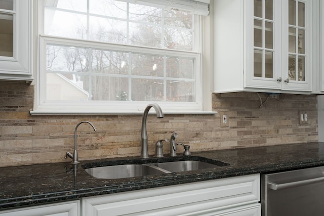 kitchen with white cabinets, stainless steel dishwasher, sink, and dark stone counters