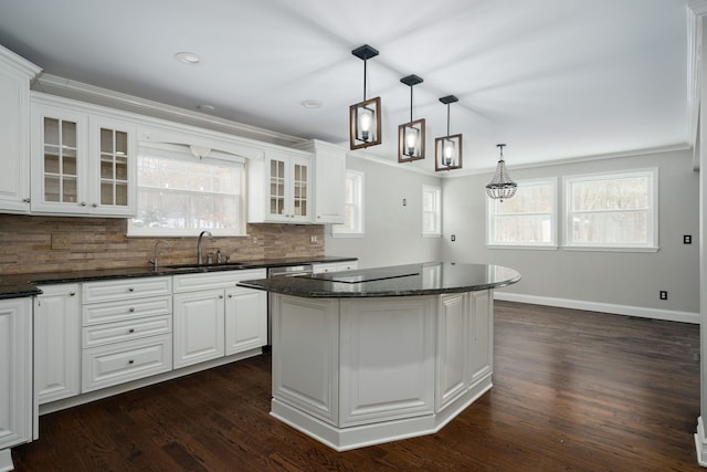 kitchen featuring decorative backsplash, sink, decorative light fixtures, white cabinets, and a center island