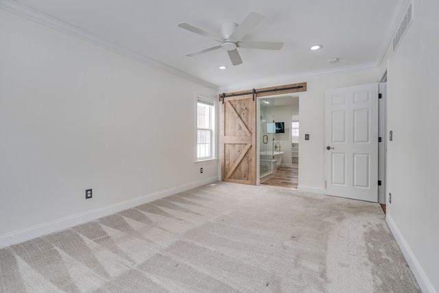 unfurnished bedroom featuring ceiling fan, a barn door, light colored carpet, and crown molding