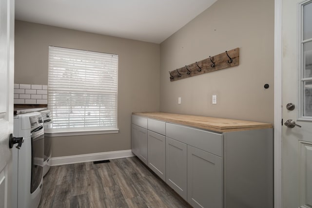 clothes washing area with cabinets, washer and clothes dryer, and dark wood-type flooring