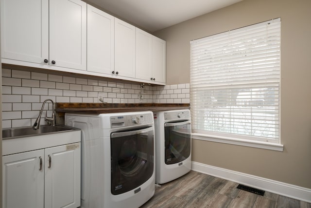 washroom featuring dark hardwood / wood-style flooring, washer and clothes dryer, cabinets, and sink